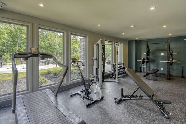 Un gimnasio con máquinas de cardio, equipo de levantamiento de pesas y bancos.