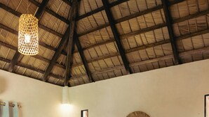 A bedroom with a wooden bed, a round mirror, and a window with curtains. - El Pueblito  (Samaná)
