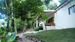 A modern house with a white exterior, a wooden staircase, and a stone pathway leading to the entrance. - El Pueblito  (Samaná)