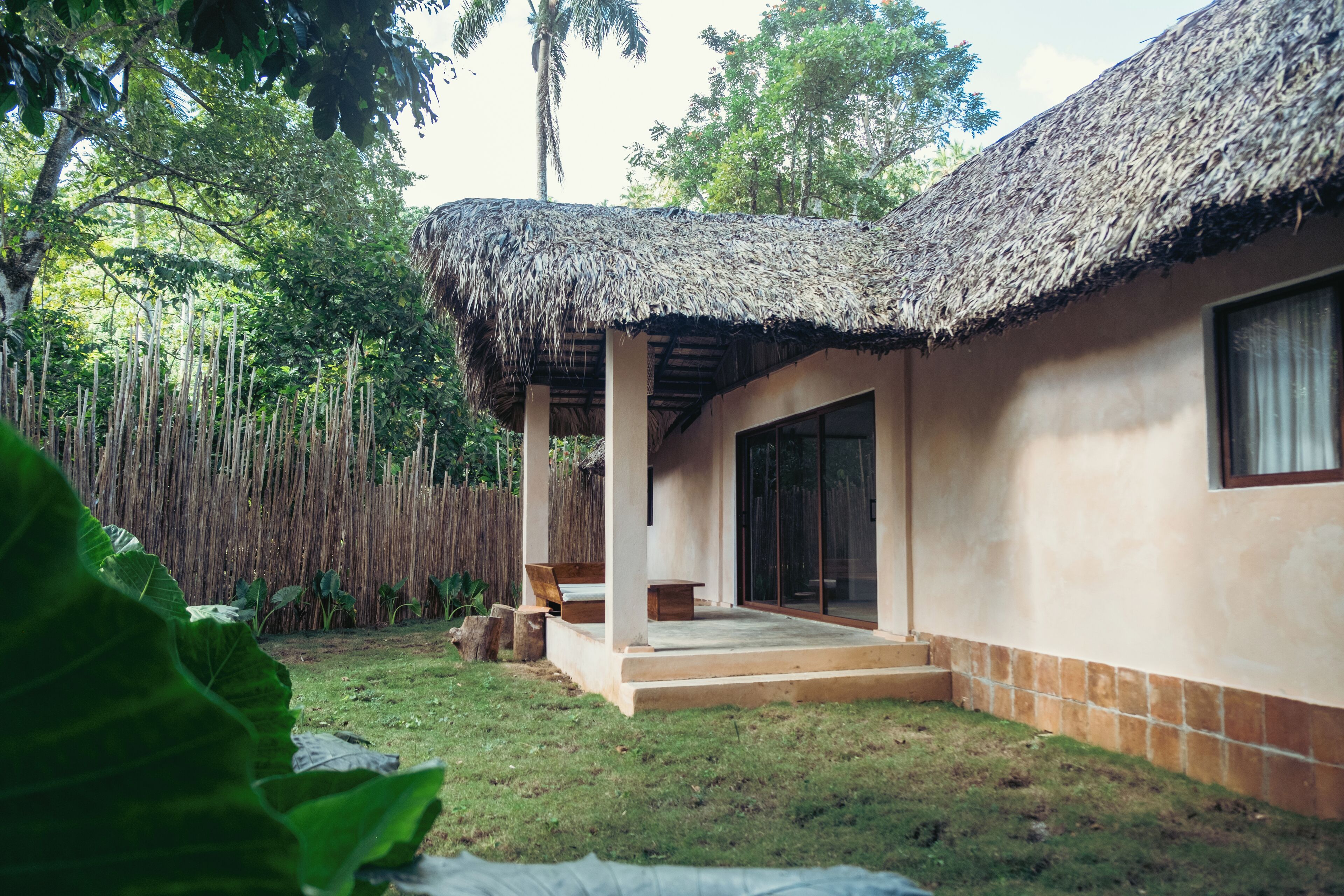 A house with a thatched roof, a covered porch, and a large window.