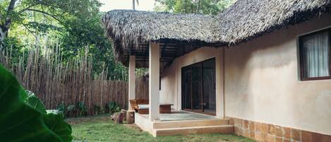 A house with a thatched roof, a covered porch, and a large window.