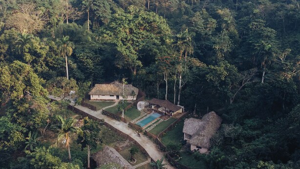 An aerial view of a secluded resort with thatched-roof cottages, a swimming pool, and lush tropical vegetation. - El Pueblito  (Samaná)