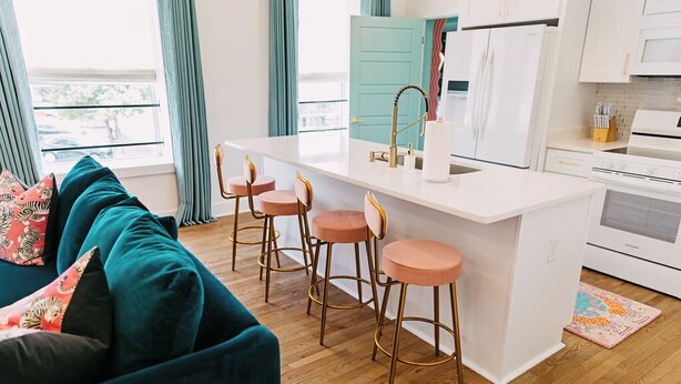A modern kitchen with a white island, bar stools, and a teal-colored door. - NEW!! Forever Young I Pettigrew Adventures in Midtown  (Memphis)