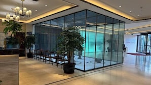 A modern lobby with a glass partition, seating area, and potted plants. - Yiyuan Hotel (Yangzhou)