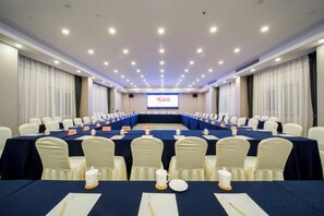 A conference room with a long table, chairs, nameplates, and a screen at the front. - Yiyuan Hotel (Yangzhou)