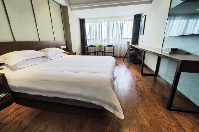 A hotel room with a large bed, a desk, and a chair.