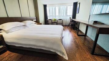 A hotel room with a large bed, a desk, and a chair.