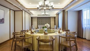 A round dining table with six chairs, a chandelier, and a decorative wall panel in the center. - Yiyuan Hotel (Yangzhou)