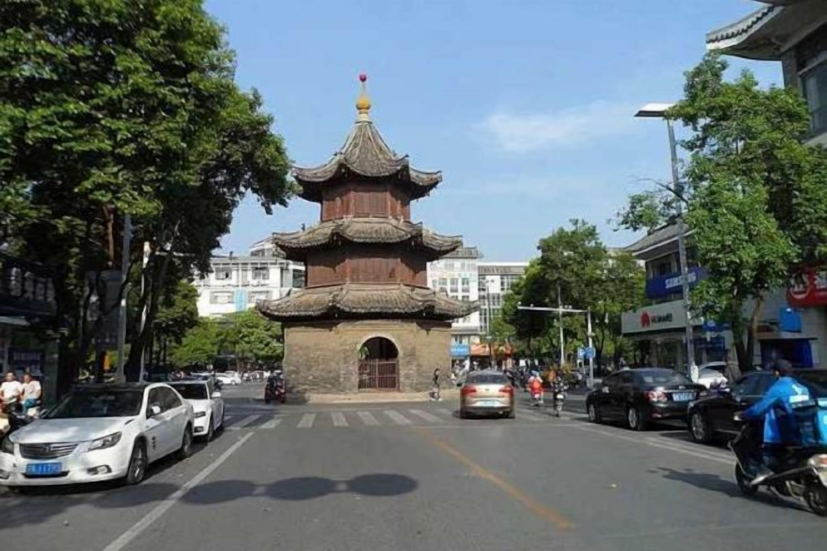 Una calle con una estructura tradicional de estilo pagoda, coches y edificios.