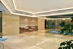 Un vestíbulo moderno con un mural grande en la pared, un panel de vidrio y un piso pulido.