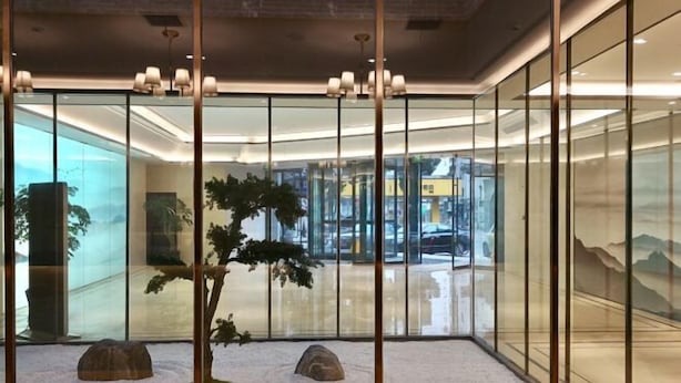 A modern interior with glass walls, a minimalist rock garden, and a view of the outside. - Yiyuan Hotel (Yangzhou)