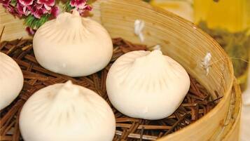 Una vaporera de bambú con varios dumplings blancos sobre una base de paja.