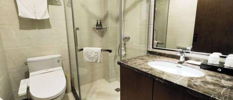A bathroom with a toilet, a glass-enclosed shower, a sink, and a large mirror.
