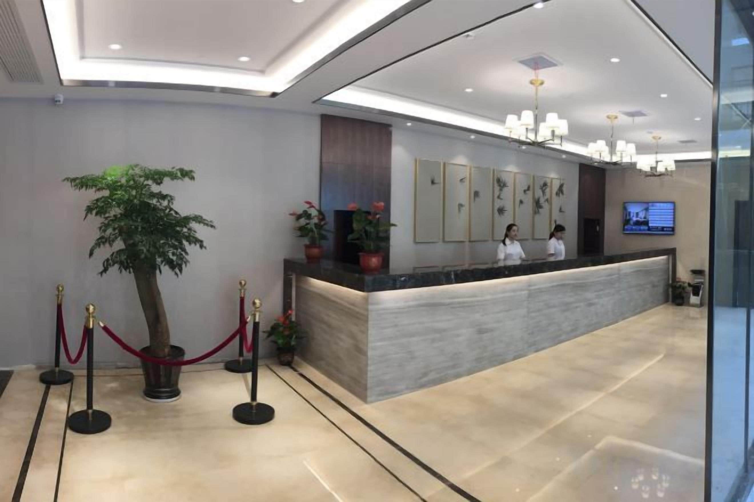 A reception area with a marble counter, a potted plant, and a television screen.