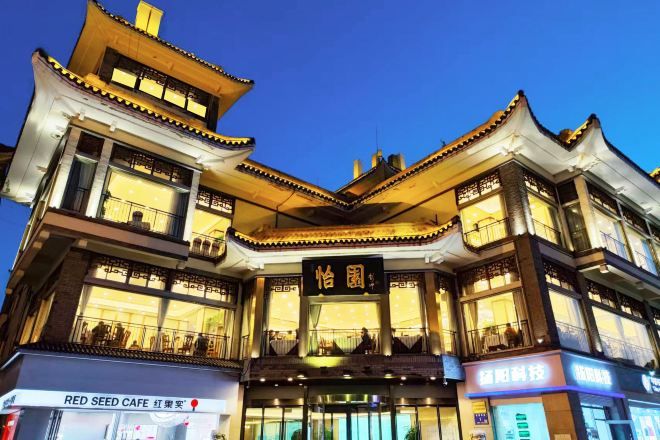 A multi-story building with traditional architectural design, featuring balconies and illuminated signage.
