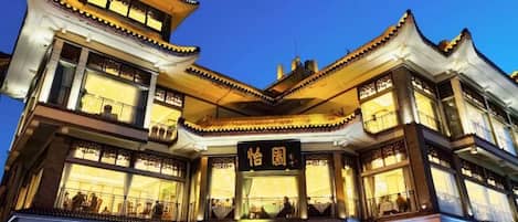 A multi-story building with traditional architectural design, featuring balconies and illuminated signage.