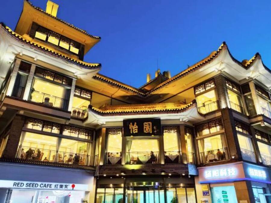 A multi-story building with traditional architectural design, featuring balconies and illuminated signage.