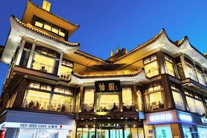 A multi-story building with traditional architectural design, featuring balconies and illuminated signage. - Yiyuan Hotel (Yangzhou)