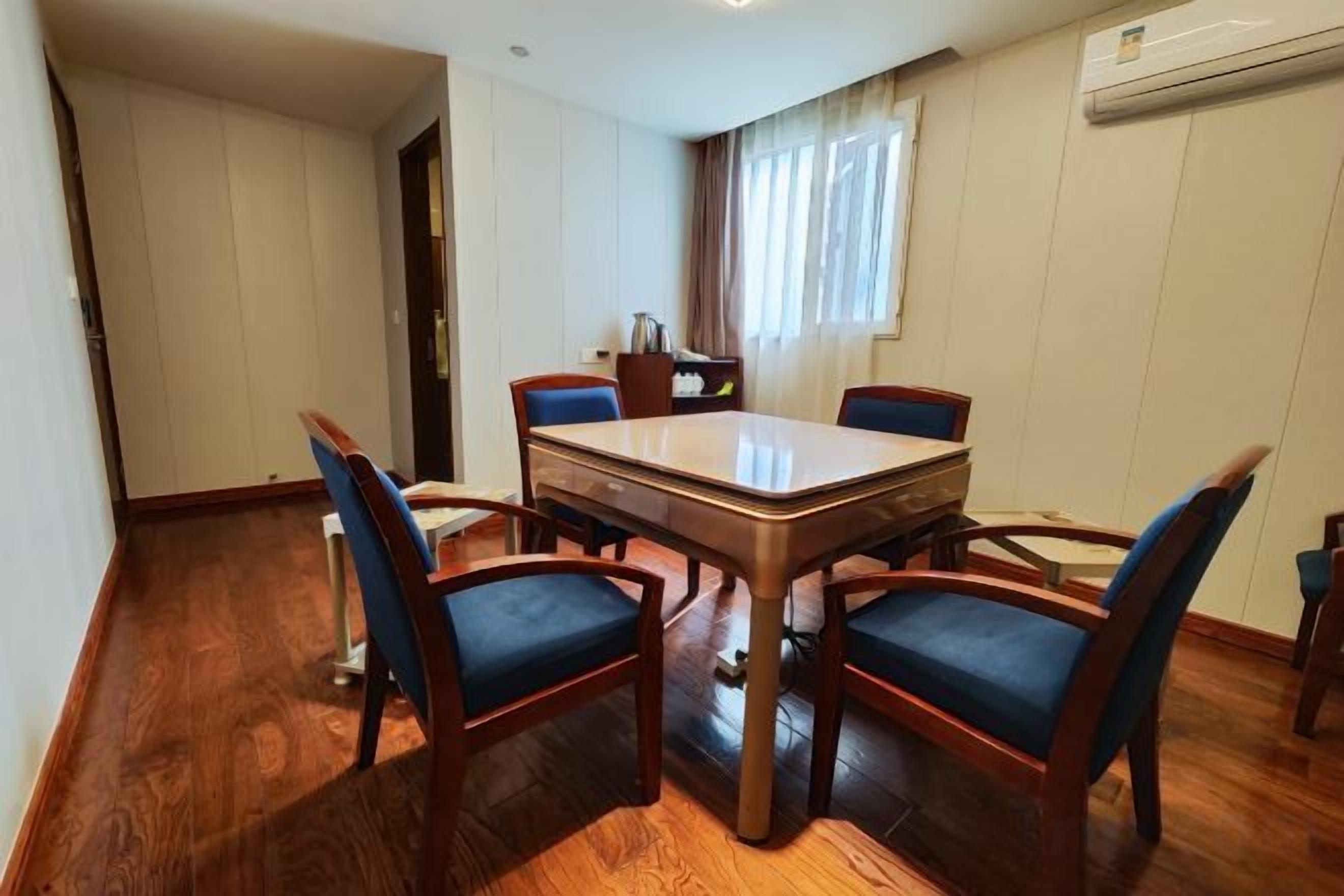 A dining area with a rectangular table and four chairs, a window with curtains, and a wooden floor.