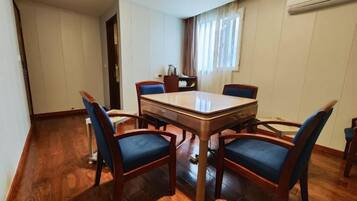 A dining area with a rectangular table and four chairs, a window with curtains, and a wooden floor.