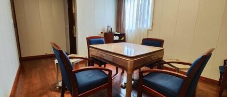 A dining area with a rectangular table and four chairs, a window with curtains, and a wooden floor.