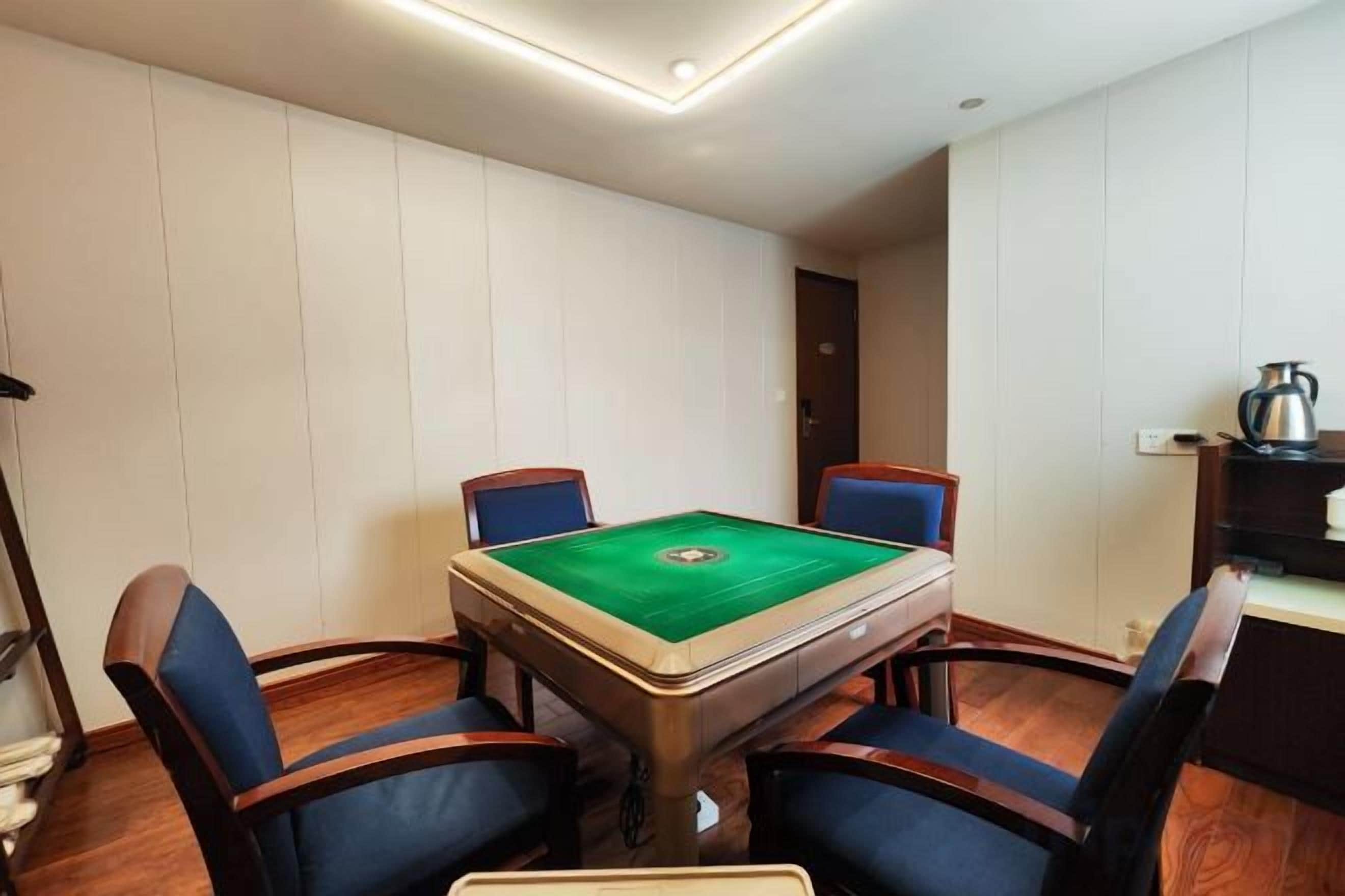 Une pièce équipée d’une table de billard, de quatre chaises et d’une petite table sur laquelle se trouve une bouilloire.