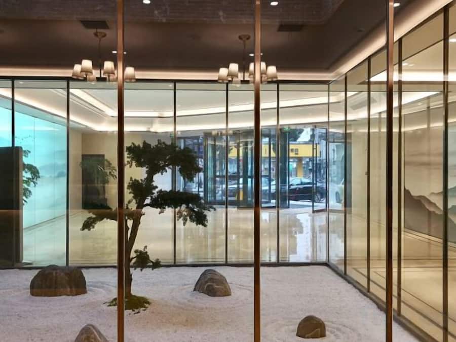A modern interior with glass partitions, a bonsai tree, and a minimalist design.