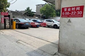 A parking area with cars and a sign indicating operating hours. - Yiyuan Hotel (Yangzhou)