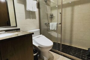 Un baño moderno con inodoro, ducha con cerramiento de vidrio y encimera de mármol.