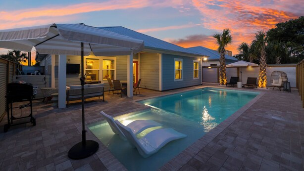 A backyard with a swimming pool, patio furniture, and a covered seating area. - Designer House-Pool-Walk 2 beach (Panama City Beach)