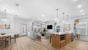 A modern kitchen with wooden cabinets, a central island, and pendant lighting. - Designer House-Pool-Walk 2 beach (Panama City Beach)