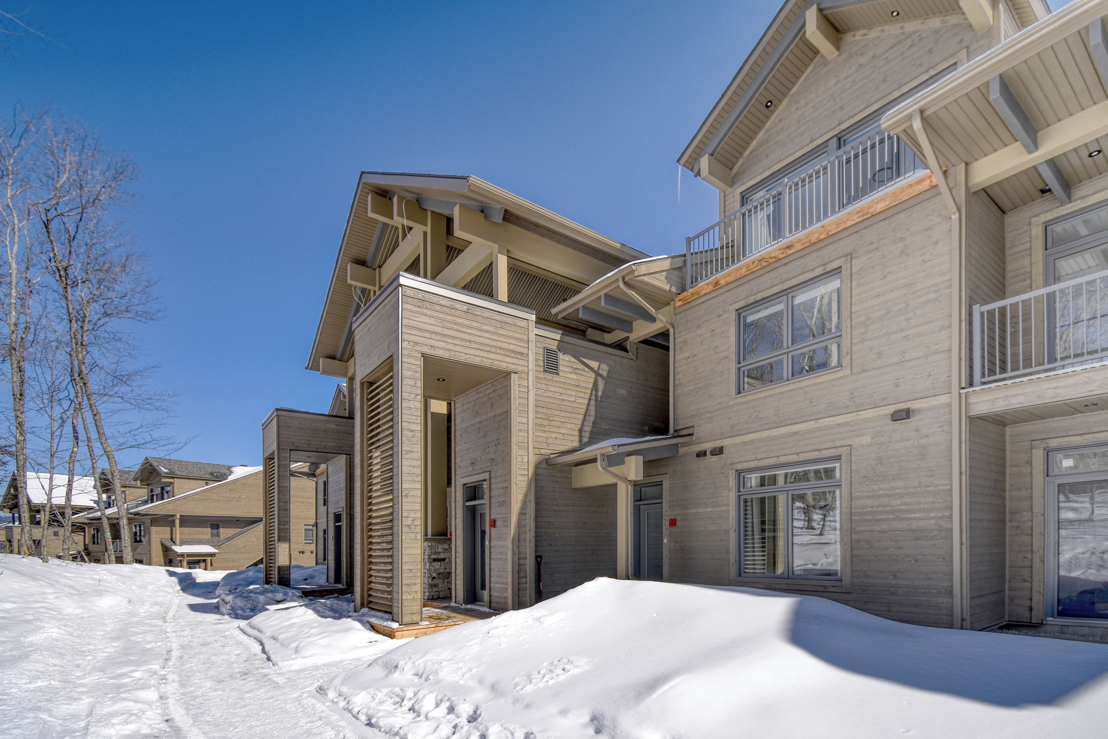 A modern multi-story building with a snow-covered ground, large windows, and a flat roof.