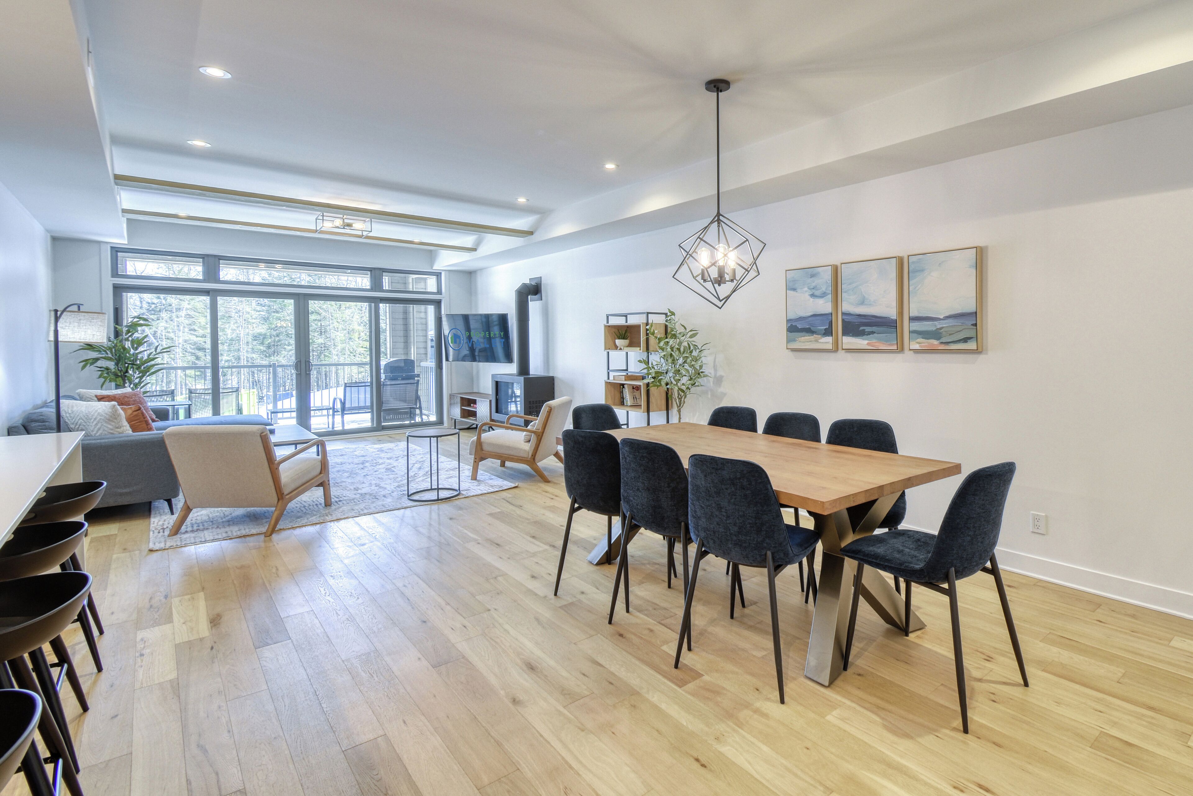 A spacious dining area with a wooden table and chairs, a sofa, and a TV in the background.
