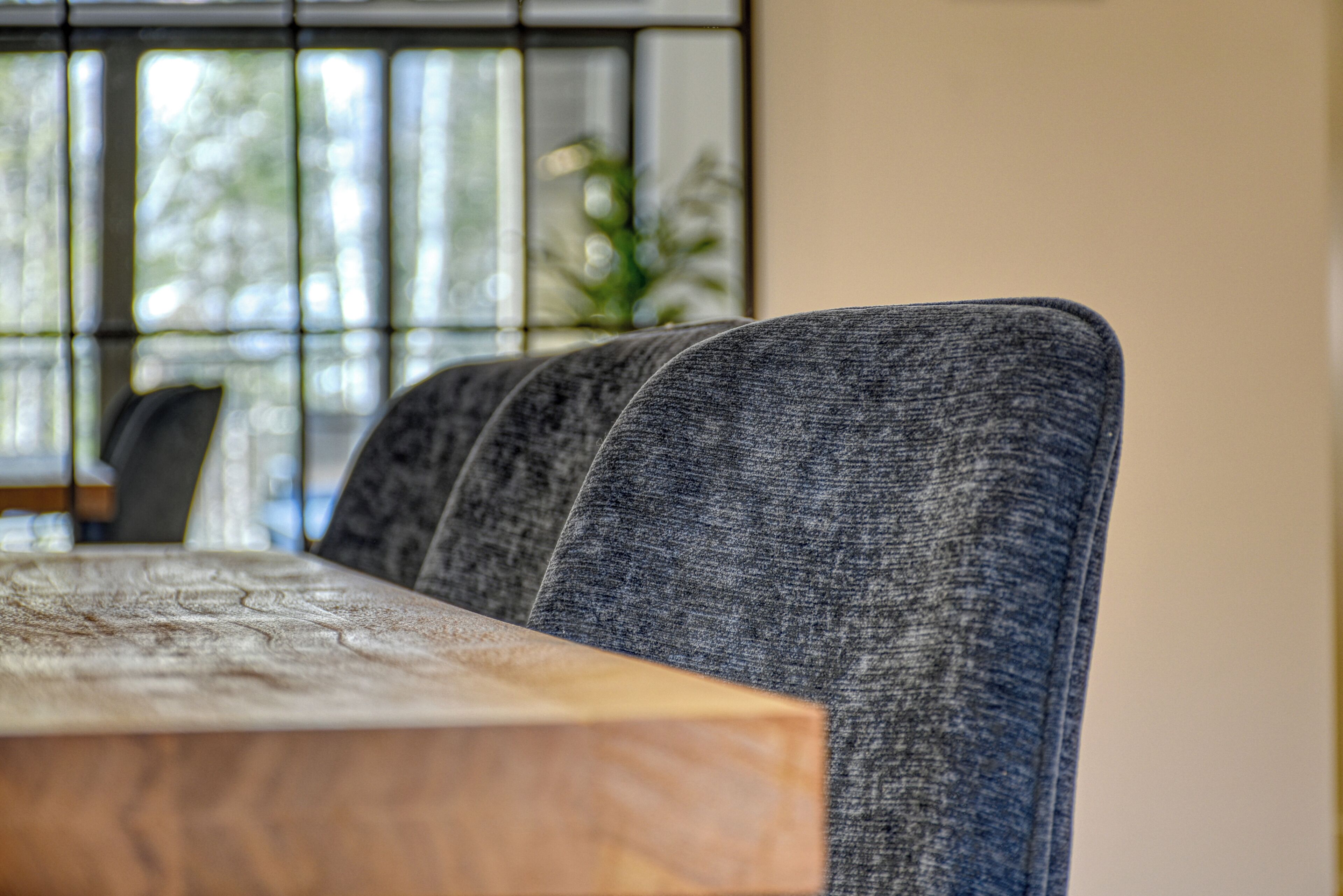 A dining area with a wooden table and grey upholstered chairs.