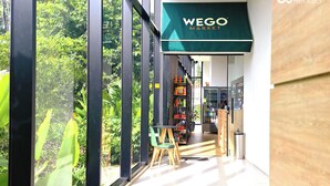 A modern interior with a green awning labeled "WEGO MARKET," large windows, and a seating area with chairs.