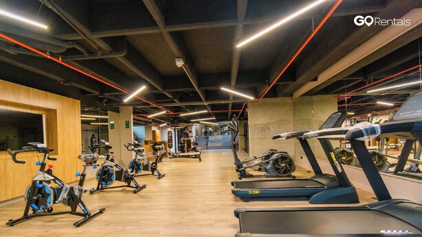 A gym with stationary bikes, treadmills, and elliptical machines.