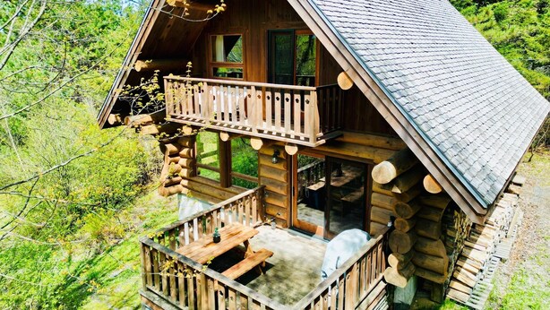 A log cabin with a balcony and a deck.