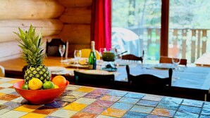 A dining table with a colorful tiled tablecloth, a bowl of fruits, and hanging pendant lights.