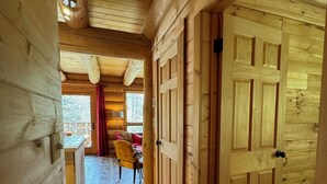 A wooden interior with a hallway leading to a room with a red curtain and a chair.