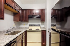 Una cocina con armarios de madera, estufa blanca y encimeras de granito.