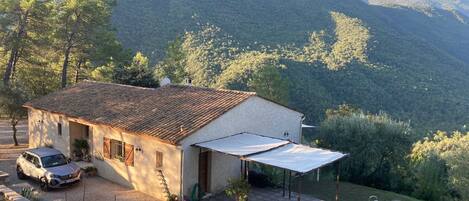 A house with a tiled roof, a patio with a pool, and a view of a mountainous landscape.