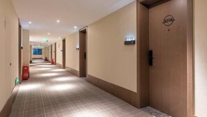 Ein Hotelkorridor mit Schachbrettmuster-Boden, Holztüren und einem Schild, das Raum Nummer 9318 anzeigt.