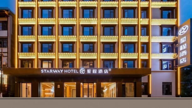 Ein mehrstöckiges Hotel mit moderner Fassade, das einen markanten Eingangsbereich und beleuchtete Schilder bietet.
