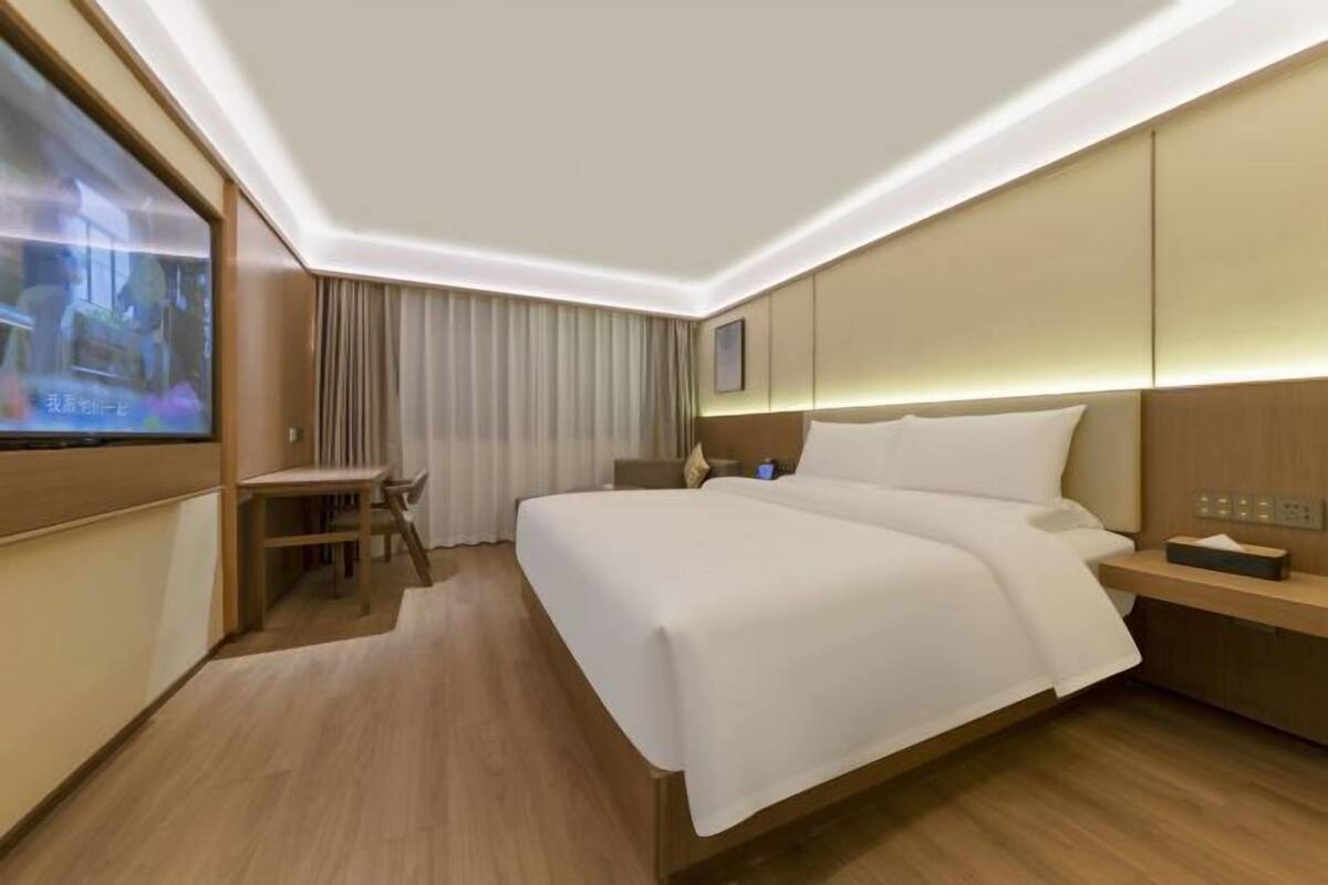 Een hotelkamer met een groot bed, een bureau en een televisiescherm.