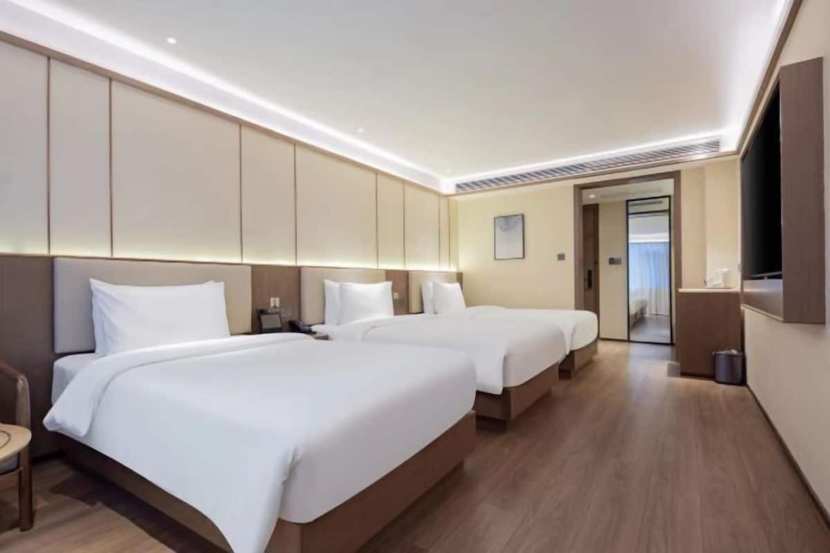 Een hotelkamer met twee bedden, een televisie en een deur naar een badkamer.