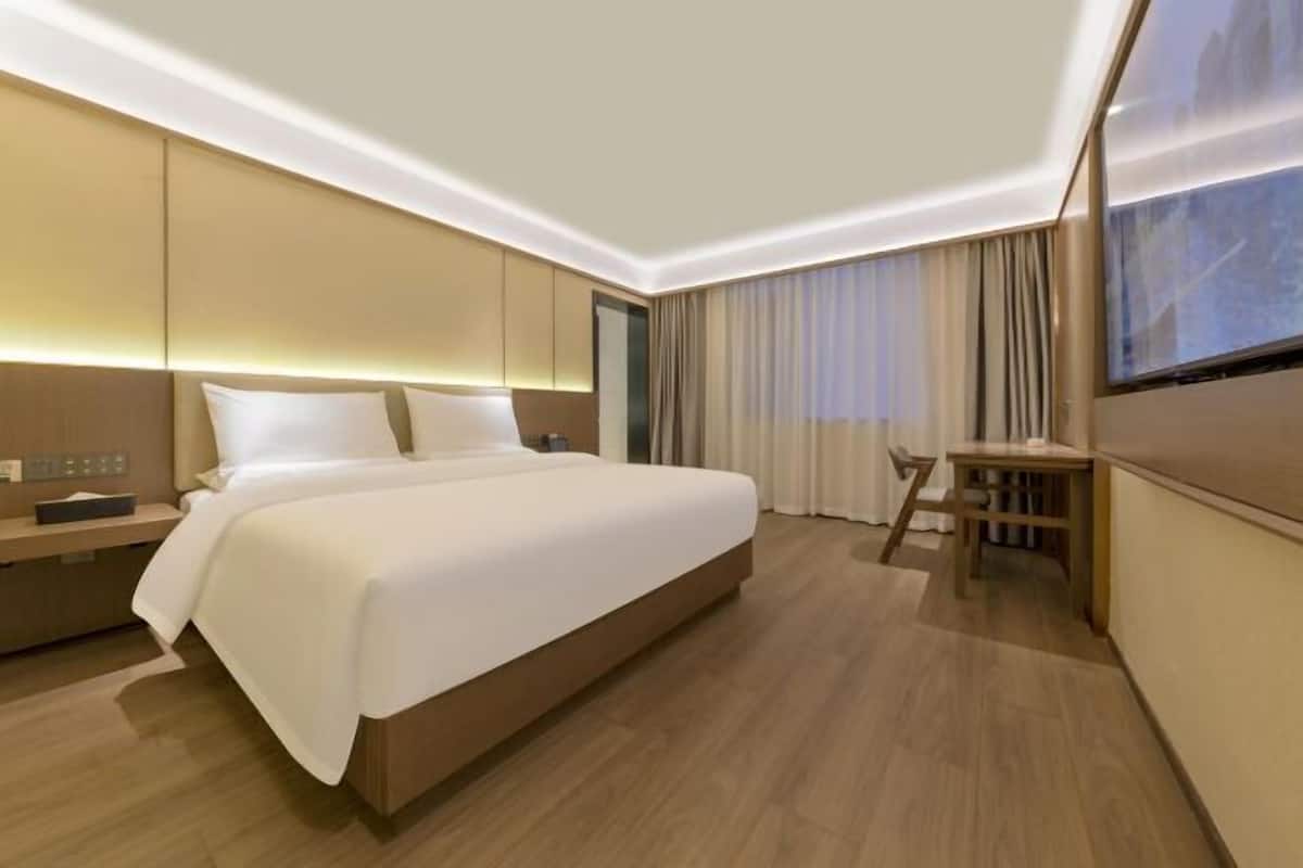 Een moderne hotelkamer met een groot bed, nachtkastje en een klein bureau.