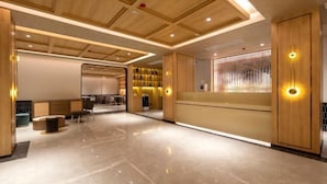 Eine moderne Hotelhalle mit Holzvertäfelung, einer Rezeption, einer Sitzecke und einem Stauraum.