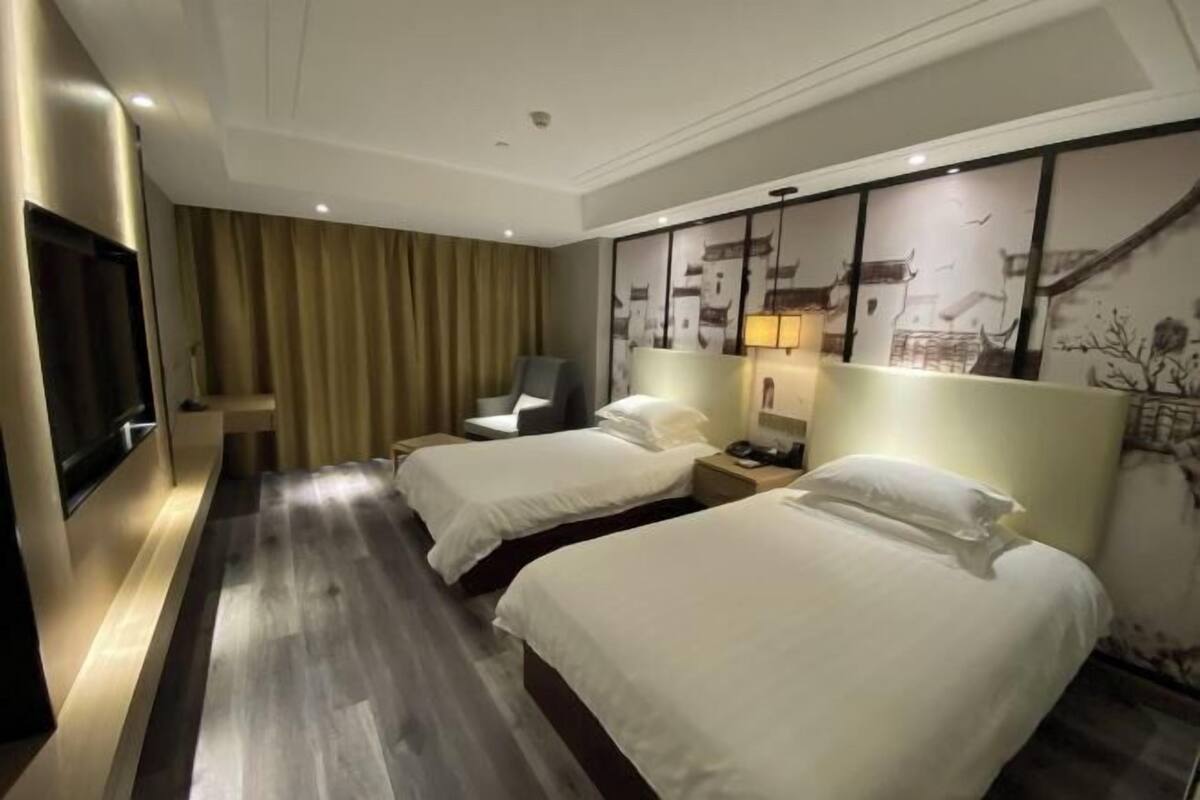 Quarto de hotel com duas camas, televisão de tela plana, escrivaninha e uma cadeira.