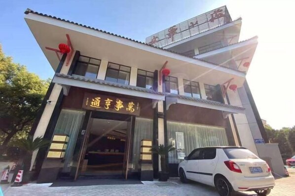 A hotel with a modern facade, a visible entrance, and a parked car in front.