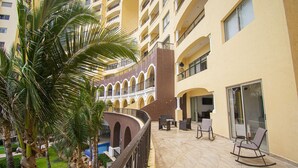 Une cour d’hôtel avec une piscine, des palmiers et des espaces de détente en plein air.